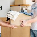 cropped-view-of-volunteers-holding-cardboard-box-with-clothes-in-charity-center.jpg